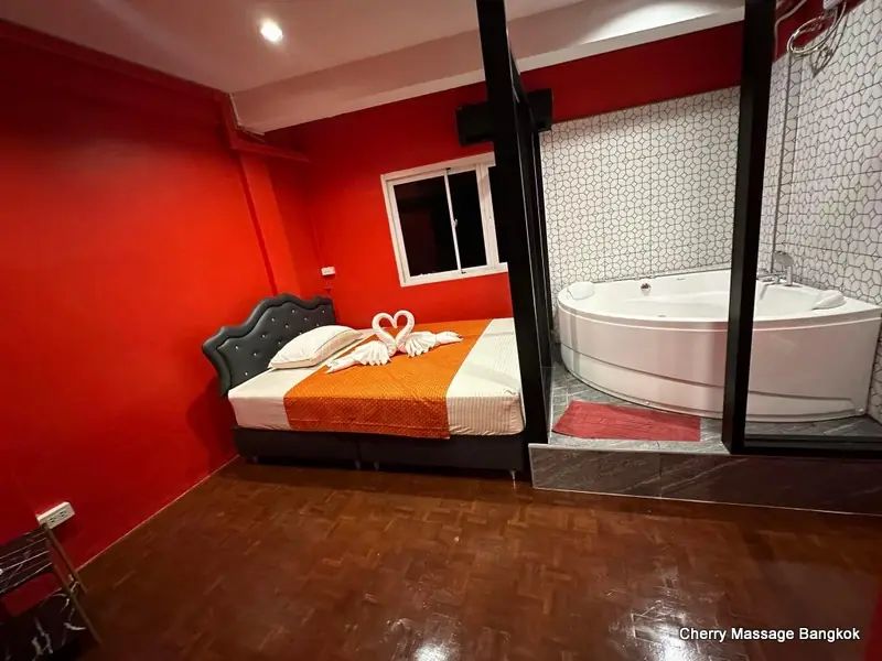 Cherry Massage Bangkok: red room with a bed and jacuzzi behind glass