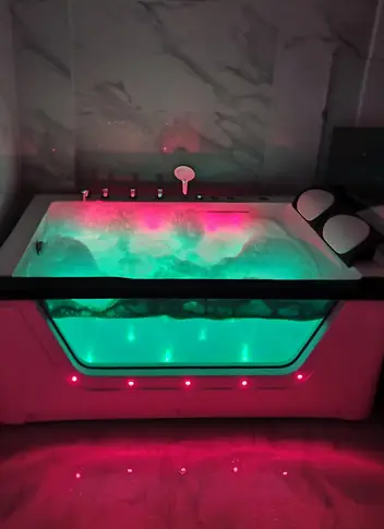 Lucy Nuru Massage: glass jacuzzi tub lit pink and green