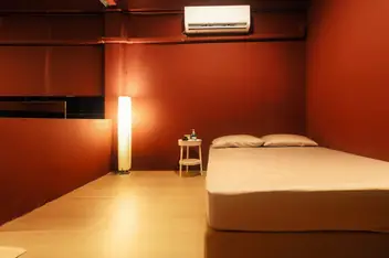 SENTO Bangkok: red-walled room with a bed and floor lamp